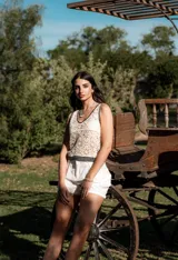 Blusa de crochet color beige con diseño calado, escote en V y terminaciones en color negro en el cuello, sisas y ruedo.