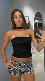 Top negro strapless, ajustado al cuerpo, con detalle de frunces horizontales en la parte delantera. Incluye un choker negro incorporado.