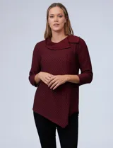 Blusa de piqué color borgoña con estampado geométrico en negro, cuello volcado y ruedo asimétrico.