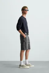 Bermuda relaxed fit confeccionada en tejido de algodón con efecto lavado. Presenta un diseño de cinco bolsillos, bolsillo multifunción en la pernera y tira lateral de estilo carpintero. Cuenta con cierre frontal con cremallera y botón.