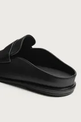 Mocasines destalonados de cuero color negro, de diseño liso con detalle de antifaz en el empeine y horma redonda.