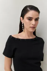 Top tejido color crudo, de silueta ajustada con diseño minimalista y escote redondo, adornado con pequeños botones metálicos.