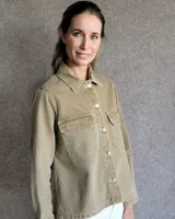 Sobrecamisa de denim azul con cuello camisero, cierre frontal con botones, mangas largas con puños abotonados y dos bolsillos con solapa en el pecho.