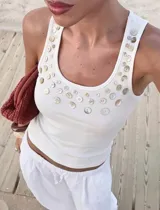 Musculosa de tejido rib color blanco, de corte ajustado y escote redondo, decorada con múltiples botones de diferentes tamaños distribuidos en la parte superior.