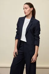 Blazer negro de líneas clásicas y silueta sastrera, con solapas y estructura definida.