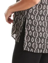 Blusa sin mangas de gasa estampada en tonos negros, grises y blancos, con escote en V pronunciado, pliegues en los hombros y ruedo asimétrico con tajos laterales.