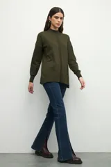 Polera negra de manga larga con puños elastizados, cuello alto y sutiles aberturas en los laterales.