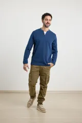 Remera de manga larga en tejido elastizado, color azul, con cuello tipo camisa, cartera con botones y detalles en eco gamuza en la base del cuello y la cartera.
