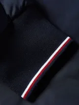 Campera bomber azul marino de poliéster reciclado, con cuello estilo béisbol, cierre de cremallera, puños y cuello de punto canalé, dos bolsillos diagonales en la cintura y detalles distintivos de Tommy Hilfiger.