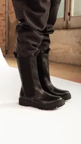 Botas negras de cuero de caña alta con suela de goma.