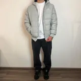 Campera inflada negra con capucha, cierre frontal blanco y puños elásticos acanalados. Presenta el logo de la marca Santa Barbara Outfitters bordado en el pecho.