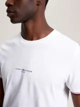 Remera blanca de algodón con corte slim, cuello redondo y mangas cortas con ribete rojo y azul. Logo de Tommy Hilfiger bordado en el pecho.