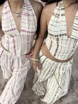 Top de cuello halter con escote en V profundo y bajo en punta. Presenta un diseño de rayas horizontales irregulares en color marrón sobre fondo beige y se ajusta mediante lazos en el cuello y la espalda.