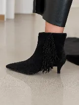 Bota de caña corta en cuero gamuzado color marrón, con diseño de punta fina y taco fino de 5 cm. Presenta un detalle de flecos laterales que aportan movimiento y estilo.