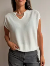 Tejido de punto de manga corta en color blanco, con escote en V y detalle de cadena metálica desmontable en el cuello. Presenta un diseño holgado y textura acanalada fina.