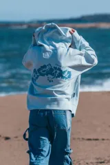 Hoodie celeste con capucha, cordones ajustables y bordado con la frase "Glassy Waves" en el pecho.