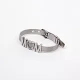 Pulsera plateada de acero con malla metálica y cierre de hebilla. Presenta la palabra "MOM" con una letra "O" en forma de corazón con incrustaciones de circonitas cúbicas.