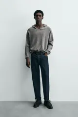 Jersey de lana gris, corte regular, con cuello pico que incorpora una capucha y manga larga. Presenta acabados en rib en puños y bajo.