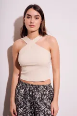 Top corto de tejido acanalado color beige claro, con escote cruzado tipo halter.