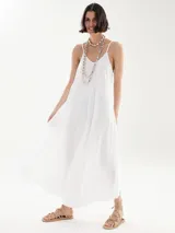 Vestido largo blanco de breteles finos, corte holgado y escote redondo. Incluye dos collares de cuentas y sandalias bajas con tiras.