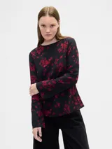Remera de manga larga con cuello bote, confeccionada en tela fluida con estampado floral en tonos rojos sobre fondo negro.