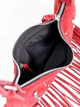 Cartera estilo hobo de cuero color rojo, con diseño semilunar, decoración de tachas metálicas plateadas y flecos largos colgantes en la parte inferior. Cuenta con correa ajustable para el hombro y forro interior con bolsillo.