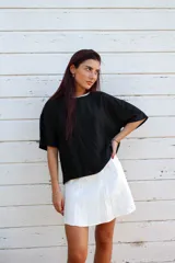 Blusa color beige de viscosa texturizada, con cuello redondo con detalle de sesgo a contratono negro, espalda con escote gota y lazo.