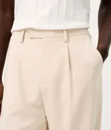 Pantalón de vestir beige de corte wide leg, con trabillas para cinto, bolsillos y diseño de sastrería.