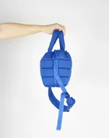 Bandolera azul acolchada con correa ajustable y asa de mano.