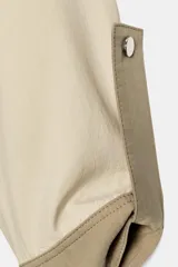 Cazadora acolchada de diseño bicolor en tonos beige y tostado, con cuello subido, manga larga con trabillas, bolsillos delanteros con botón a presión y cierre frontal de botones a presión.