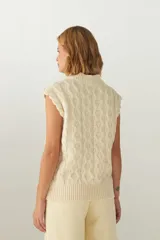 Chaleco de punto color crema con diseño trenzado y cuello en V.