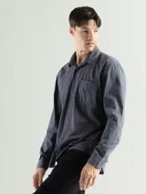 Camisa de manga larga color gris oscuro, confeccionada en algodón, con cuello clásico, cierre frontal con botones, bolsillo de parche en el pecho y corte clásico.