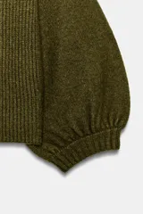 Jersey corto de punto en color verde oliva, con cuello redondo y mangas abullonadas de largo tres cuartos terminadas en puño elástico.