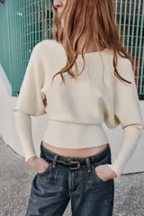 Jersey de punto color verde lima, con cuello pico y manga larga de sisa ancha que se estrecha hacia la muñeca.