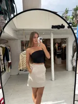 Pollera corta de cuero sintético con diseño de paneles y bolsillos frontales grandes. Presenta un corte recto y tiro medio.