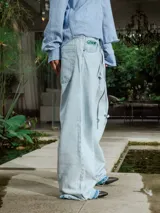 Pantalón de jean celeste lavado, de corte ancho y tiro alto con cordón ajustable en la cintura. Presenta detalles deshilachados en los bajos.