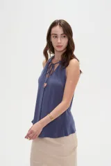Musculosa de viscosa color rojo, con cuello halter, corte ajustado al cuerpo y detalle de cordones con cuentas en el escote.