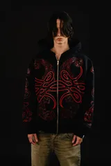 Hoodie con cierre frontal completo, confeccionado en algodón de tejido grueso. Presenta un diseño estampado en serigrafía con motivos de hojas de acanto en color rojo sobre fondo negro. Cuenta con bolsillos laterales y cierre metálico YKK.