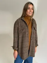 Sobrecamisa de lana con estampado de cuadros en tonos tierra, corte oversize, cuello camisero, cierre frontal de botones y bolsillos delanteros con solapa.