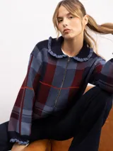 Campera de punto con diseño de cuadros tartán en tonos azul, bordó y naranja. Presenta un corte holgado, cierre frontal con cremallera y un cuello estilo babero con volados decorativos en los bordes.