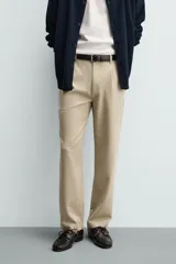 Pantalón de corte recto confeccionado en tejido elástico, con cintura elástica, pliegues frontales, bolsillos laterales y bolsillos traseros de vivo con botón.