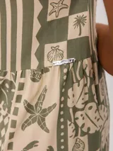 Vestido largo de algodón con estampado estilo patchwork en tonos verde y beige, escote en V con tirantes finos ajustables, diseño holgado y falda escalonada con bolsillos laterales.