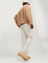 Pantalón cargo color beige de corte relajado, con cierre de gancho y cremallera, bolsillos traseros, frontales y laterales, tiro medio y detalle de cordones en los dobladillos.