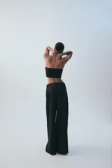 Pantalón de tiro medio color marrón, con pinzas en el delantero, perneras anchas de corte recto y trabillas para cinturón. Cuenta con bolsillos laterales y traseros, y cierre frontal con cremallera y botón.
