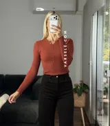 Remera de punto acanalado con escote redondo y cierre frontal parcial con botones. Presenta mangas largas y un ajuste entallado al cuerpo.