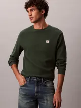 Remera de manga larga Calvin Klein en color verde oscuro, confeccionada en tejido térmico de punto con textura de nido de abeja. Cuenta con cuello redondo, puños acanalados y un pequeño parche con el logo de la marca en el pecho.