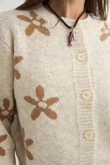 Cardigan de punto con estampado de flores, cuello redondo y cierre frontal con botones. Presenta un diseño de corte holgado con puños y ruedo acanalados.