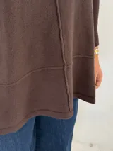 Sweater de punto color chocolate, con cuello alto acanalado, mangas largas y diseño holgado con costuras verticales y horizontales visibles.