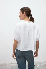 Camisa blanca de lino con cuello mao, manga corta y cierre frontal con botones.