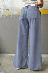 Pantalón de jean color crudo, de corte palazzo con aberturas en el ruedo y bolsillos laterales.